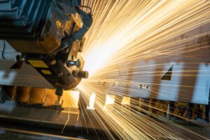 A large manufacturing machine works on a product with sparks flying; is this an example of sustainability in manufacturing?